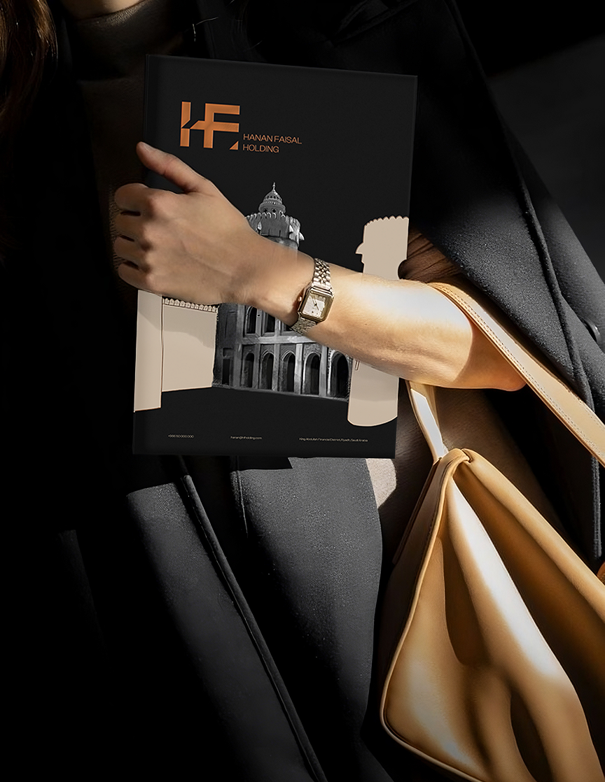 Close-up of a woman carrying a Hanan Faisal Holding branded folder and a beige handbag